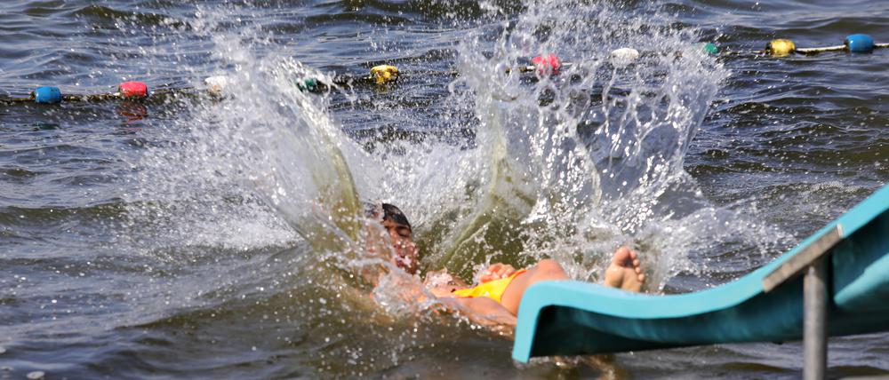 Wasser spritzt als ein Badegast im Strandbad in die Havel springt.