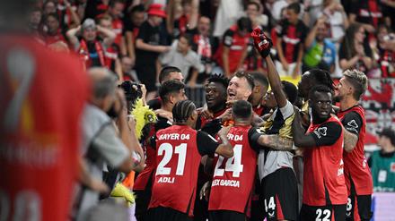 Bayer Leverkusen's players celebrate with Finnish goalkeeper #01 Lukas Hradecky after winning the penalty shoot-out of the German Supercup football match between Bayer 04 Leverkusen and VfB Stuttgart in Leverkusen, western Germany on August 17, 2024. (Photo by Sascha Schuermann / AFP) / DFL REGULATIONS PROHIBIT ANY USE OF PHOTOGRAPHS AS IMAGE SEQUENCES AND/OR QUASI-VIDEO