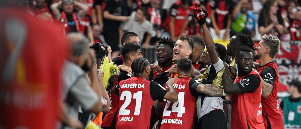 Bayer Leverkusen's players celebrate with Finnish goalkeeper #01 Lukas Hradecky after winning the penalty shoot-out of the German Supercup football match between Bayer 04 Leverkusen and VfB Stuttgart in Leverkusen, western Germany on August 17, 2024. (Photo by Sascha Schuermann / AFP) / DFL REGULATIONS PROHIBIT ANY USE OF PHOTOGRAPHS AS IMAGE SEQUENCES AND/OR QUASI-VIDEO