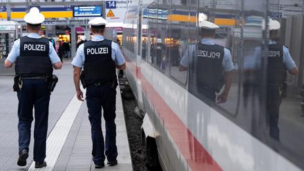 Bundespolizisten gehen am Hauptbahnhof München an einem Bahnsteig an einem ICE entlang.