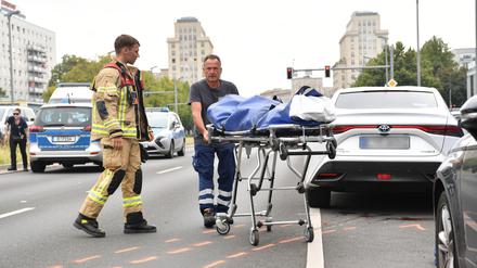 Ein Mitarbeiter der Gerichtsmedizin transportiert auf der Karl-Marx-Allee einen Leichnam ab. Ein 41 Jahre alter Fußgänger ist am Morgen in Berlin-Mitte von einem Auto überfahren worden und ums Leben gekommen.