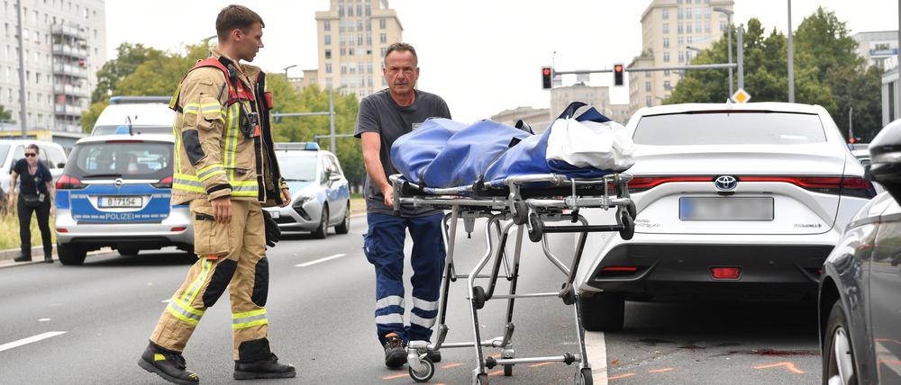 Ein Mitarbeiter der Gerichtsmedizin transportiert auf der Karl-Marx-Allee einen Leichnam ab. Ein 41 Jahre alter Fußgänger ist am Morgen in Berlin-Mitte von einem Auto überfahren worden und ums Leben gekommen.