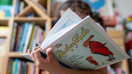 Ein Mädchen hält eine neuere Ausgabe des Kinderbuch-Klassikers „Die Häschenschule“.