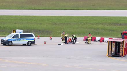 Einsatzkräfte von Polizei und Feuerwehr stehen auf einer Zufahrt für Start- und Landebahnen am Flughafen Franz-Josef-Strauß um Klimaaktivisten, die sich dort festgeklebt haben (Symbolbild).