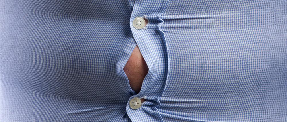 Das blaue Hemd eines übergewichtigen Mannes kurz vor dem Aufplatzen.