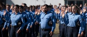 Angehende Brandenburger Polizeibeamtinnen und -beamte stehen anlässlich ihrer Vereidigung auf dem Gelände der Hochschule der Polizei in Oranienburg.
