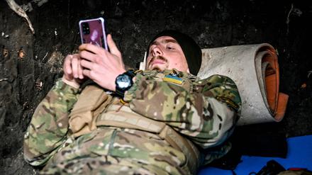 Ein Soldat der ukrainischen Streitkräfte, der die Richtung Saporischschja bewacht, sieht in einem Unterstand in der Ukraine auf seinem Handy nach (Archivbild vom 3. November 2022).