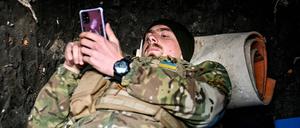 Ein Soldat der ukrainischen Streitkräfte, der die Richtung Saporischschja bewacht, sieht in einem Unterstand in der Ukraine auf seinem Handy nach (Archivbild vom 3. November 2022).