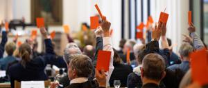 Teilnehmer der Tagung der Landessynode der Evangelischen Kirche Berlin-Brandenburg-schlesische Oberlausitz (EKBO) in der St.-Bartholomäus-Kirche halten ihre Stimmkarten hoch. Nach einem Beschluss der Landessynode verliert ein AfD-Politiker seine Kirchenämter.