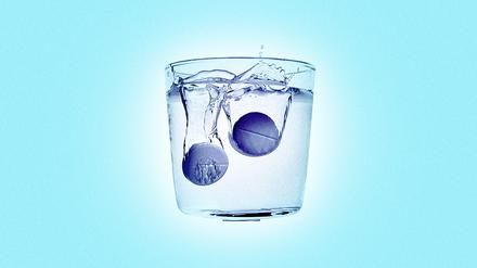 Zwei Aspirin-Tabletten lösen sich in einem Wasserglas auf. 