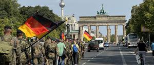 Bundeswehrsoldaten marschieren mit Deutschlandflaggen auf das Brandenburger Tor zu. (Archivbild)