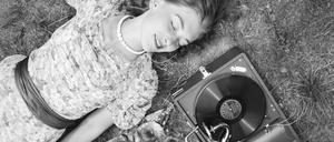 Zwei junge Frauen liegen im Gras und hören die neuesten Schlager vom Electrola Koffergrammophon, Deutschland 1930er Jahre. 