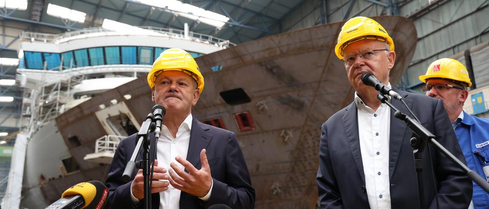 Bundeskanzler Olaf Scholz (SPD, l) und Stephan Weil (SPD), Ministerpräsident von Niedersachsen, geben in einer Werkshalle der Meyer Werft ein Presse-Statement ab. Im Hintergrund der Betriebsratsvorsitzende der Meyer-Werft, Andreas Hensen. 