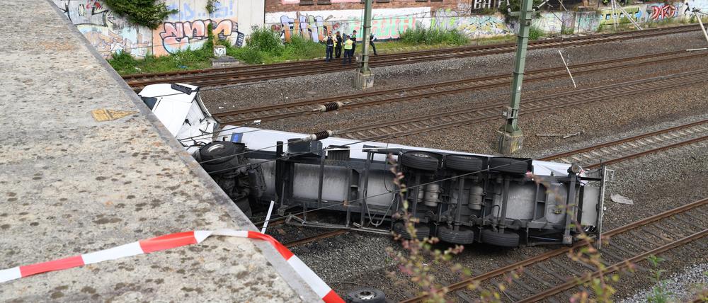 Ein Lastwagen liegt am Freitag nach dem Sturz von einer Brücke auf Bahngleisen.