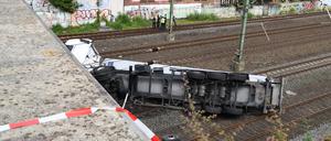 Ein Lastwagen liegt am Freitag nach dem Sturz von einer Brücke auf Bahngleisen. 