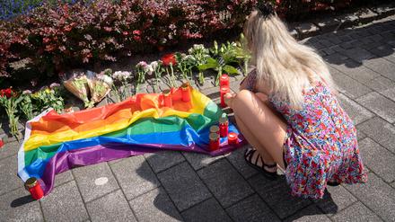 Eine Frau an einer Gedenkstelle mit Blumen, Kerzen und einer Regenbogenflagge in Solingen.
