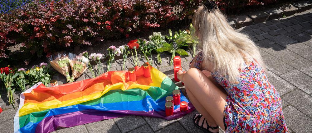 Eine Frau an einer Gedenkstelle mit Blumen, Kerzen und einer Regenbogenflagge in Solingen.