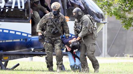 Der mutmaßliche Täter des Messerangriffs von Solingen wird von einem Hubschrauber zu einer Wagenkolonne geführt. Diese bringt ihn zum Ermittlungsrichter des Bundesgerichtshof (BGH), der über einen Haftbefehl entscheiden wird.