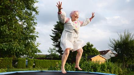 Eine ältere Frau springt glücklich auf einem Trampolin. (Symbolbild)