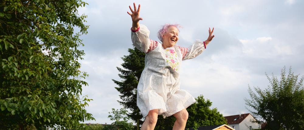 Eine ältere Frau springt glücklich auf einem Trampolin. (Symbolbild)