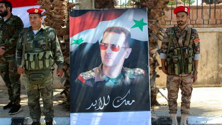 Soldaten nehmen Aufstellung rechts und links eines Bildes von Bashar al-Assad, dem Staatspräsidenten Syriens.