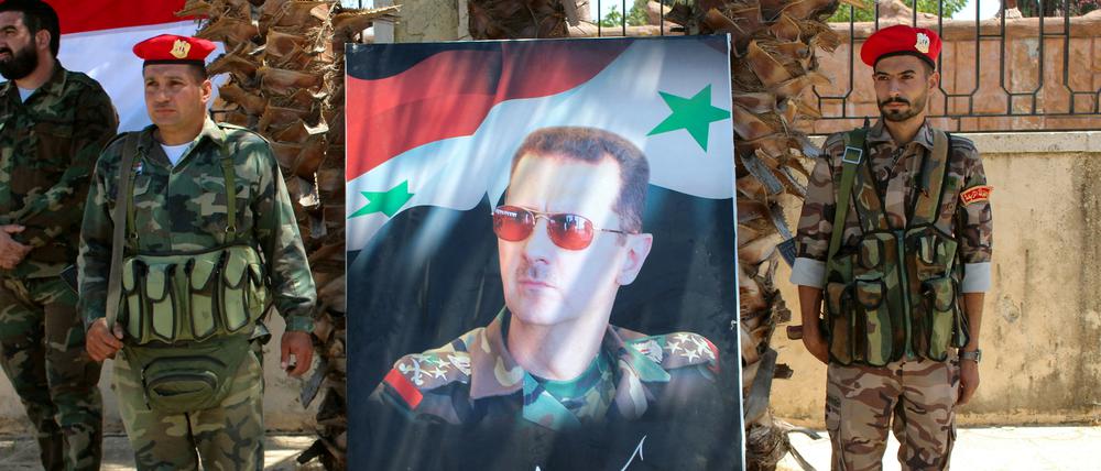 Soldaten nehmen Aufstellung rechts und links eines Bildes von Bashar al-Assad, dem Staatspräsidenten Syriens.