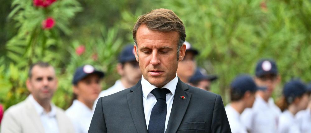 Der französische Präsident Emmanuel Macron betrachtet zwei Smartphones während einer Zeremonie zum 80. Jahrestag der Landung der Alliierten in der Provence während des Zweiten Weltkriegs auf dem Nationalfriedhof Boulouris.