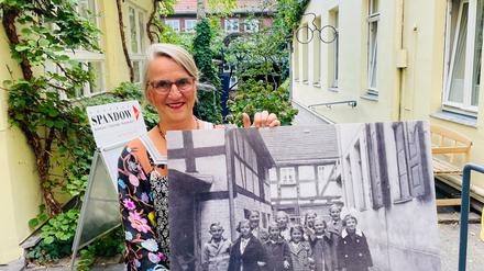 Katrin Weimershausen im Hof, in der Hand ein Foto aus den 60er Jahren.