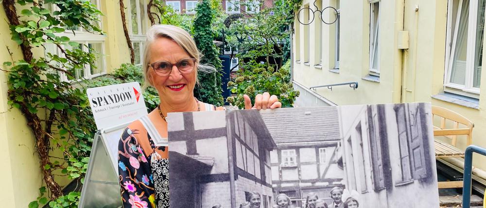 Katrin Weimershausen im Hof, in der Hand ein Foto aus den 60er Jahren.