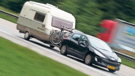 Ein Auto mit Wohnwagen-Anhänger fährt auf der Autobahn A8, aufgenommen am 02.07.2014 bei Holzkirchen (Symbolbild).