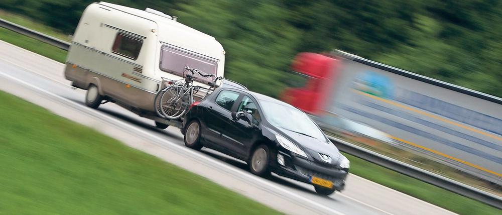 Ein Auto mit Wohnwagen-Anhänger fährt auf der Autobahn A8, aufgenommen am 02.07.2014 bei Holzkirchen (Symbolbild).