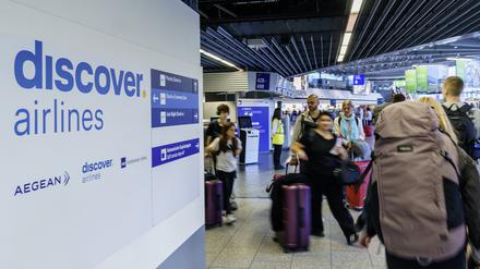 Reisende gehen am Frankfurter Flughafen zum Check-in an den Schaltern von Discover Airlines vorbei. 