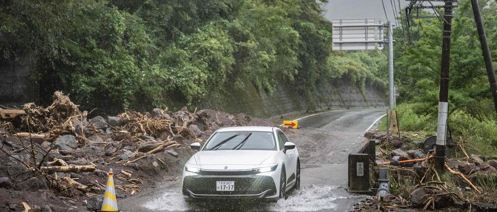 Ein Auto fährt am 29. August 2024 durch eine überflutete Straße in der Stadt Yufu in der Präfektur Oita. Der Taifun Shanshan, einer der stärksten Taifune Japans seit Jahrzehnten, ließ am 29. August sintflutartige Regenfälle über südlichen Regionen niedergehen, wobei eine Person vermisst wurde und die Behörden vor lebensbedrohlichen Überschwemmungen und Erdrutschen warnten.