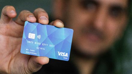 Eine Person hält eine Debitcard in der Hand. 