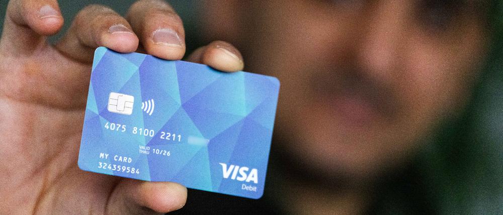 Eine Person hält eine Debitcard in der Hand.