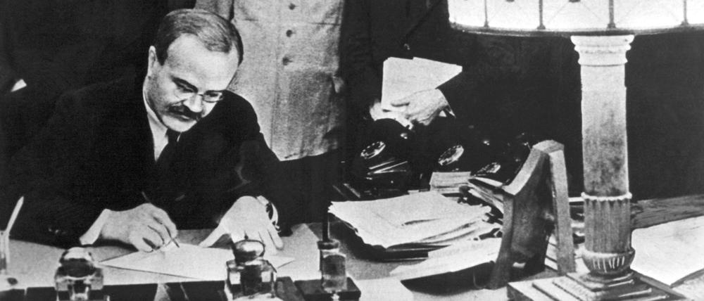 Wjatscheslaw Michailowitsch Molotow, Vorsitzender des UdSSR-Rats, unterzeichnet den Hitler-Stalin-Pakt in Moskau (1939). Hinter ihm: der NS-Außenminister Joachim von Ribbentrop und Josef Stalin.