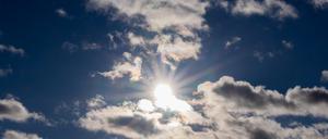 Die Sonne scheint zwischen Wolken hindurch.  