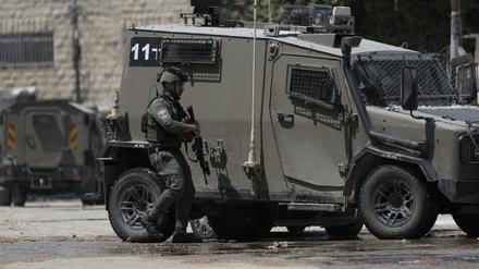 Ein Angehöriger der israelischen Streitkräfte geht neben einem gepanzerten Fahrzeug während einer Militäroperation im Westjordanland (Symbolbild).