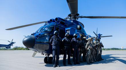 Einsatzkräfte der GSG 9 und der Bundespolizei-Fliegerstaffel stehen zusammen vor einem Hubschrauber „Super Puma“. 