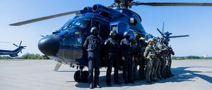 Einsatzkräfte der GSG 9 und der Bundespolizei-Fliegerstaffel stehen zusammen vor einem Hubschrauber „Super Puma“. 