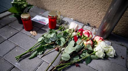 Blumen und Kerzen liegen nach einem tödlichen Messerangriff vor einem Hauseingang in Berlin-Friedrichsfelde neben einem Zettel mit der Aufschrift „Man tötet nicht aus Liebe - Stoppt Femizide“.