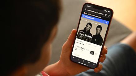 Ein Fan versucht mit seinem Smartphone ein Ticket für die Oasis-Comback-Tour zu kaufen.