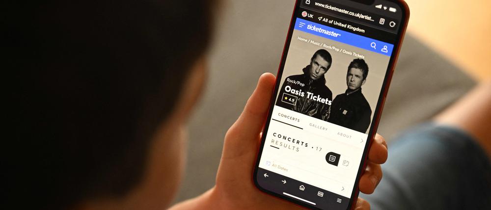 Ein Fan versucht mit seinem Smartphone ein Ticket für die Oasis-Comback-Tour zu kaufen.