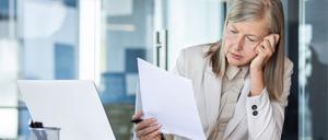 Ältere Arbeitnehmerin bäugt sich über ein Schriftstück. Menschen Ü50 haben es bei der Jobsuche schwerer.