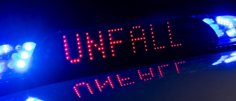Das Blaulicht auf einem Fahrzeug der Polizei leuchtet in der Dunkelheit, während auf dem Display der Hinweis «Unfall» zu lesen ist.