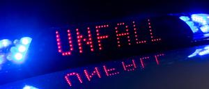Das Blaulicht auf einem Fahrzeug der Polizei leuchtet in der Dunkelheit, während auf dem Display der Hinweis «Unfall» zu lesen ist.