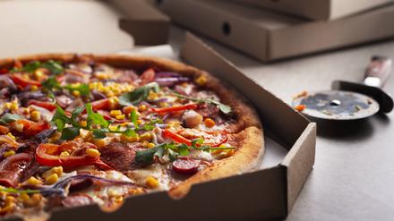 Large Pizza in open carton box and cutter on kitchen table closeup view Large Pizza in open carton box and cutter on kitchen table closeup view Copyright: xZoonar.com/OlenaxMykhaylovax 21034229