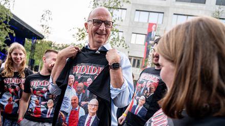Dietmar Woidke (SPD), Brandenburgs Ministerpräsident, hält auf dem SPD-Sommerfest in Potsdam ein T-Shirt mit Bildern von sich in der Hand. 