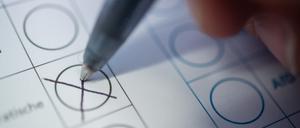 Eine Person macht ein Kreuz auf einem Wahlzettel.