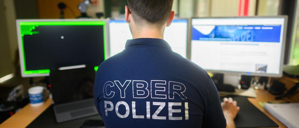 Ein Polizist steht mit einem Poloshirt mit Aufschrift ·Cyber Polizei·.